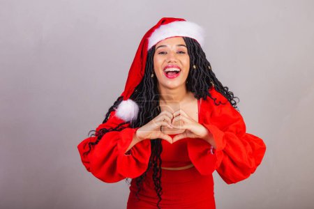 Photo for Brazilian black woman, wearing christmas clothes, merry christmas, smiling, heart sign. - Royalty Free Image