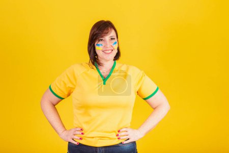 Téléchargez les photos : Femme rousse, fan de football brésilien. les mains sur les hanches. - en image libre de droit