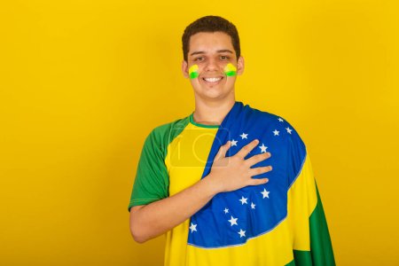 Foto de Joven aficionado al fútbol brasileño. vestido de verde, mano sobre pecho, gratitud, himno nacional. - Imagen libre de derechos