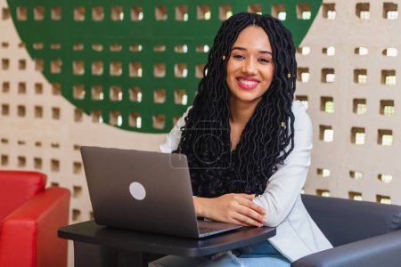 Téléchargez les photos : Jeune femme noire, brésilienne, étudiante universitaire étudiant sur son carnet, enseignement et technologie. - en image libre de droit