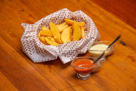 Foto de Papas fritas rústicas, un aperitivo típico brasileño, servido con mayonesa y salsa de chile. - Imagen libre de derechos