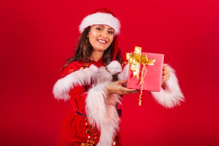 Téléchargez les photos : Femme brésilienne vêtue de vêtements de Noël, le Père Noël. remettre à la caméra un cadeau rouge. - en image libre de droit