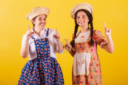 Téléchargez les photos : Grand-mère et petite-fille vêtues de vêtements typiques de Festa Junina. Danse, célébration et fête. - en image libre de droit