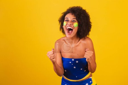 Téléchargez les photos : Jeune femme noire fan de football brésilien. hurlant objectif - en image libre de droit