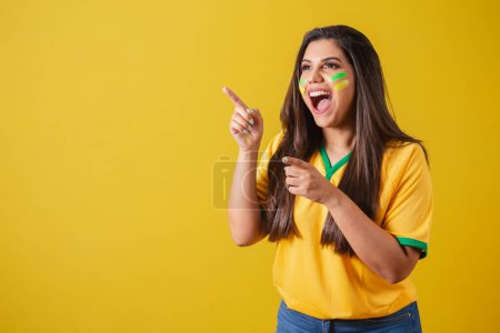 Téléchargez les photos : Femme supporter du Brésil, coupe du monde 2022, championnat de football, surprise, incroyable, pointant du doigt vers la gauche. - en image libre de droit