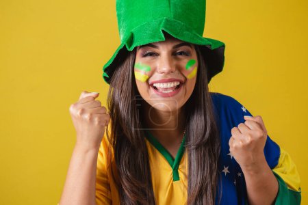 Foto de Foto de cerca, Mujer partidaria de Brasil, Copa del Mundo 2022, celebrando, vistiendo traje de abanico, bandera y sombrero. - Imagen libre de derechos