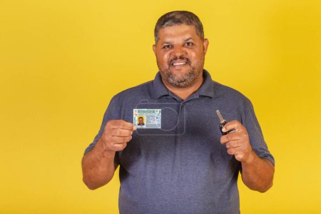 Téléchargez les photos : Homme noir brésilien, adulte avec permis de conduire, document brésilien et clé de voiture. - en image libre de droit
