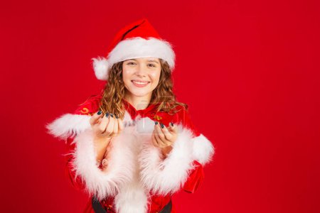 Téléchargez les photos : Brésilien, femme caucasienne vêtue de vêtements de Noël, Père Noël. bienvenue, invitant avec les mains. - en image libre de droit