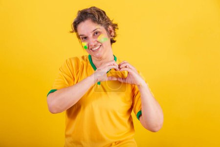 Foto de Adulto adulto mujer, fútbol fan de brasil, corazón signo con las manos, amor. - Imagen libre de derechos