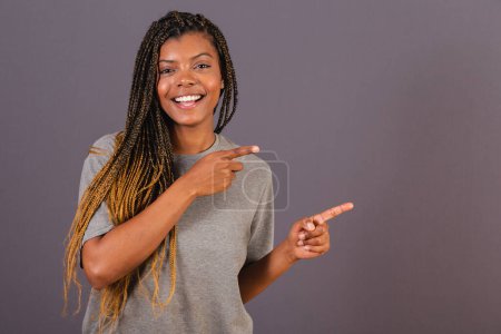 Téléchargez les photos : Jeune femme afro brésilienne pointant avec les doigts vers la droite. Photo pour annonce. Publicité. - en image libre de droit