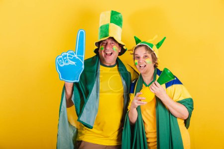 Téléchargez les photos : Couple adulte, fan de football brésilien, drapeau et chapeau. Cheering et faire la fête. - en image libre de droit