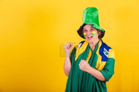 Photo for Adult adult woman, brazil soccer fan, wearing flag and hat, partying in match. - Royalty Free Image