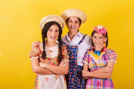 Foto de Abuela y sus dos nietas vestidas con ropa típica de Festa Junina. Mirando a la cámara, sonriendo. - Imagen libre de derechos
