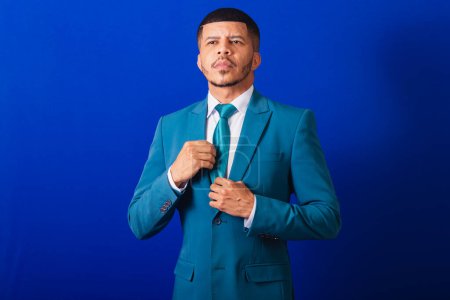 Photo for Brazilian black man, dressed in a suit and blue tie. business man. fixing tie - Royalty Free Image