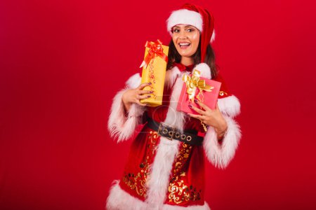 Téléchargez les photos : Femme brésilienne vêtue de vêtements de Noël, le Père Noël. étreignant deux cadeaux. - en image libre de droit