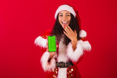 Foto de Hermosa mujer negra brasileña, vestida como santa claus, ropa de Navidad. celebración del teléfono celular, con pantalla de croma. - Imagen libre de derechos