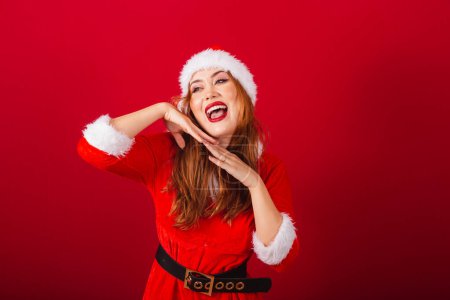 Téléchargez les photos : Belle femme rousse brésilienne, vêtue de vêtements de Noël, le Père Noël. faire des expressions et des grimaces. - en image libre de droit