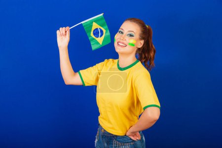 Photo for Caucasian woman, redhead, Brazilian soccer fan, Brazilian, blue background, waving flag of Brazil. - Royalty Free Image