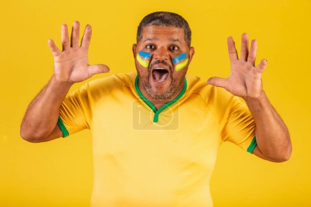 Foto de Hombre negro brasileño, fanático del fútbol de Brasil. sorprendida, guau, increíble, increíble. - Imagen libre de derechos