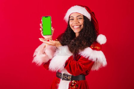 Foto de Hermosa mujer negra brasileña, vestida como santa claus, ropa de Navidad. celebración del teléfono celular, con pantalla de croma. - Imagen libre de derechos