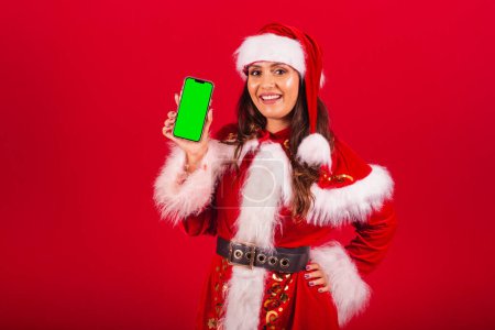 Foto de Mujer brasileña vestida con ropa de Navidad, Santa Claus. sostener smartphone con pantalla verde en croma. - Imagen libre de derechos