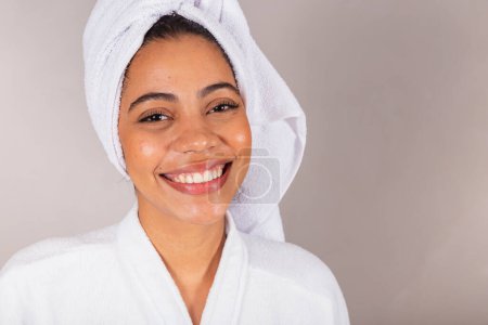 Téléchargez les photos : Belle femme noire brésilienne, portant peignoir et serviette. Gros plan photo, sourire, dents, bien-être. - en image libre de droit