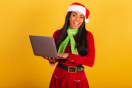 Foto de Hermosa mujer brasileña negra, vestida con ropa de Navidad, Papá Noel, sosteniendo el cuaderno. - Imagen libre de derechos
