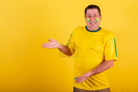 Foto de Hombre adulto, fanático del fútbol brasileño, presentando algo a su izquierda. - Imagen libre de derechos