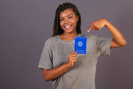 Foto de Joven mujer afro brasileña con carnet de trabajo y seguridad social. Documento oficial, Recursos humanos, mercado laboral. - Imagen libre de derechos