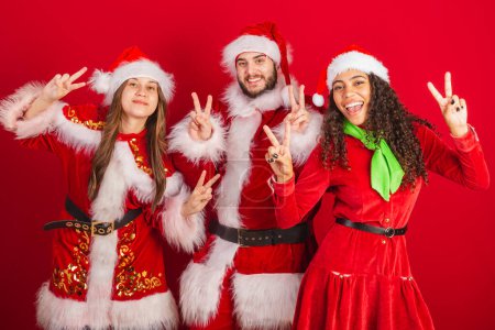 Photo for Brazilian friends with christmas clothes, santa claus. peace and love, pose for photo. - Royalty Free Image