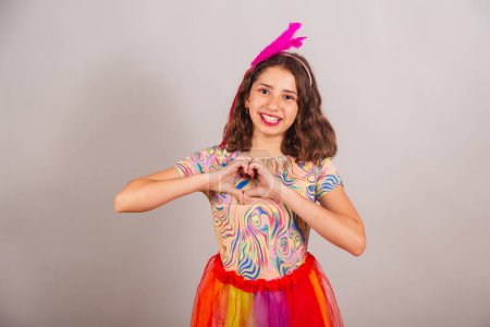 Foto de Niño brasileño, niña, vestido con traje de carnaval, signo del corazón con las manos. - Imagen libre de derechos