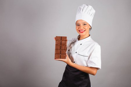 Photo for Head chef, Brazilian cook, from the Northeast, holding a bar of chocolate, specialist in the preparation of chocolate. Easter. - Royalty Free Image