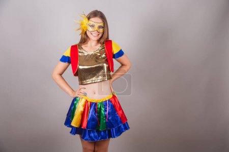 Téléchargez les photos : Femme blonde brésilienne, vêtue de vêtements frevo, masque de carnaval et la main sur sa taille. - en image libre de droit