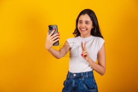 Photo for Beautiful brazilian woman holding smartphone, taking self portrait, selfie. - Royalty Free Image