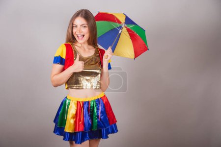 Téléchargez les photos : Femme blonde brésilienne vêtue de vêtements frevo, carnaval. avec parapluie frevo coloré. signe positif avec les doigts. Genre - en image libre de droit