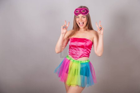 Foto de Mujer rubia brasileña vestida con ropa de carnaval rosa. máscara, pose para la foto, la paz y el amor. - Imagen libre de derechos