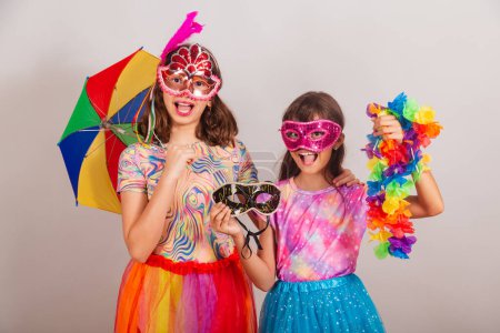 Téléchargez les photos : Deux enfants brésiliens, filles, habillées en tenue de carnaval, tenant accessoires de carnaval. - en image libre de droit