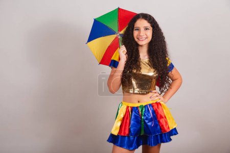 Téléchargez les photos : Jeune adolescente, brésilienne, avec des vêtements frevo, carnaval. avec parapluie et mains sur la taille. - en image libre de droit