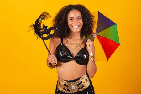 Photo for Beautiful black Brazilian woman, in Cleopatra carnival clothes, holding carnival mask and colorful umbrella. - Royalty Free Image