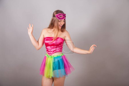 Foto de Mujer rubia brasileña vestida con ropa de carnaval rosa. usando rímel, bailando. - Imagen libre de derechos