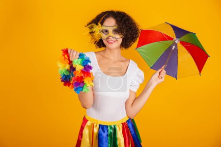 Foto de Hermosa mujer brasileña, vestida con ropa de carnaval, falda colorida y camisa blanca. sosteniendo collar de flores, invitando al carnaval. - Imagen libre de derechos