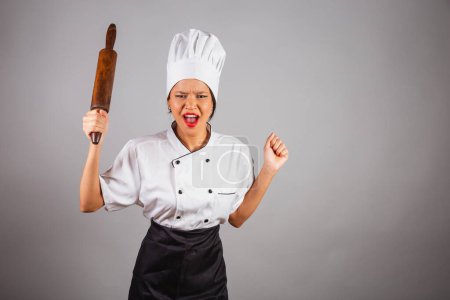 Photo for Head chef, Brazilian cook, from the Northeast, holding a wooden rolling pin for preparing bread and pasta. stressed - Royalty Free Image