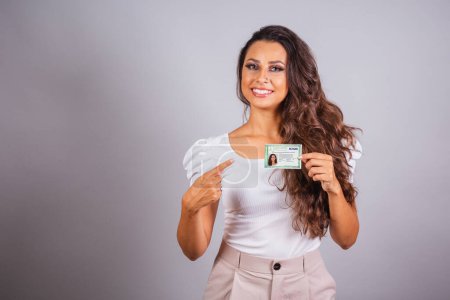 Photo for Brazilian woman, brown hair, holding identity card, RG, Brazilian document. - Royalty Free Image