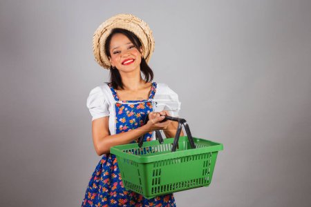 Photo for Brazilian woman, northeastern, with June party clothes, straw hat. holding market basket,shopping for So Joo party. - Royalty Free Image