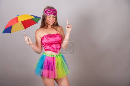 Téléchargez les photos : Femme blonde brésilienne vêtue de vêtements de carnaval rose. portant un masque, avec un parapluie frevo. Danse. - en image libre de droit