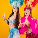 two brazilian female friends with queen clothes from samba school, carnival. Feather crown. dancing and partying