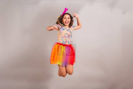 Téléchargez les photos : Enfant brésilien, fille, habillée en tenue de carnaval, sautant pour la photo. - en image libre de droit