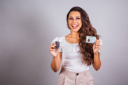 Photo for Brazilian woman, brown hair, holding driver's license, Brazilian document and car key, new car. - Royalty Free Image
