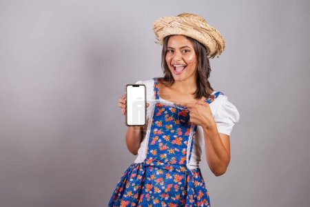 Foto de Mujer brasileña vistiendo ropa de campo, fiesta So Joo, fiesta Junina. con smartphone y pantalla para publicidad y publicidad. - Imagen libre de derechos