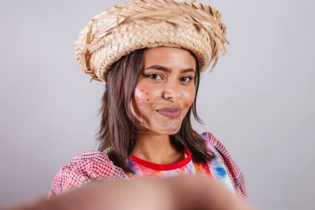 Photo for Brazilian woman wearing country clothes, So Joo party, Junina party. taking self portrait with smartphone, selfie. - Royalty Free Image